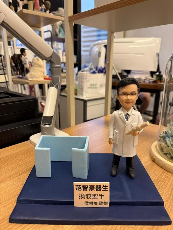 客製醫師公仔展示於藍色場景與銘牌底座，穿白袍手持病歷卷軸，醫護致敬與感謝禮物首選