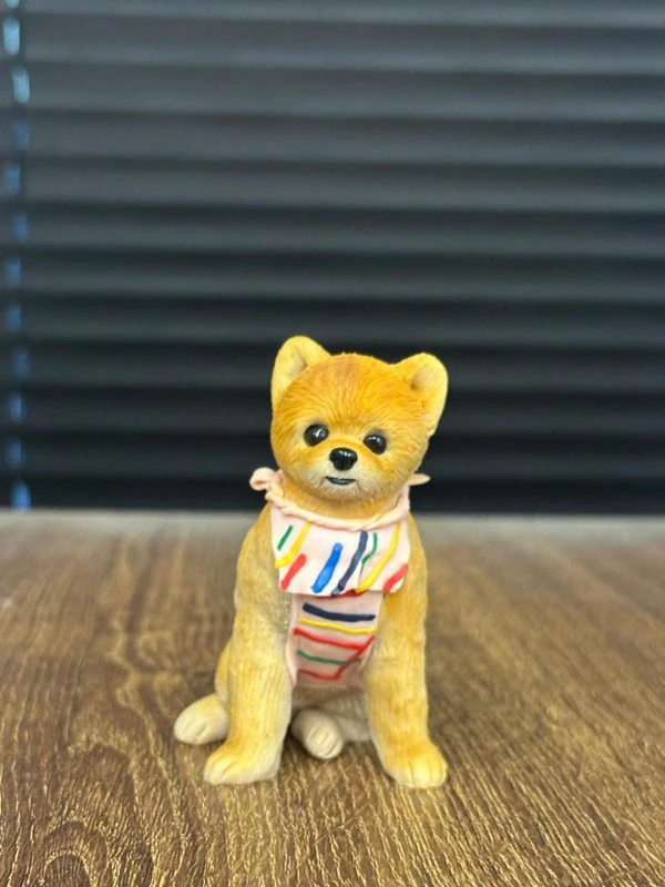 這款狗狗造型的客製化寵物公仔，由 CUTEFIGURE HK 團隊全手工製作，以安全無毒的軟陶材料雕塑出細膩的毛髮紋理與自然姿態。公仔採用坐姿設計，搭配色彩繽紛的圍巾，營造俏皮又溫馨的氛圍。每隻寵物公仔皆以相片作藍本，手工捏製比例、體態、毛色與獨特特徵，確保能忠實呈現愛寵獨一無二的個性。