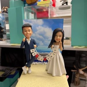 雙人婚禮公仔手拉日期旗串,沙灘背景與金色銘牌,結婚與週年紀念浪漫客製